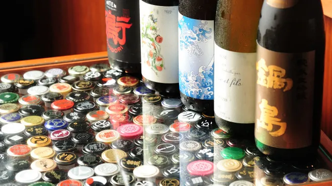Sake bottles on a counter covered with bottle caps