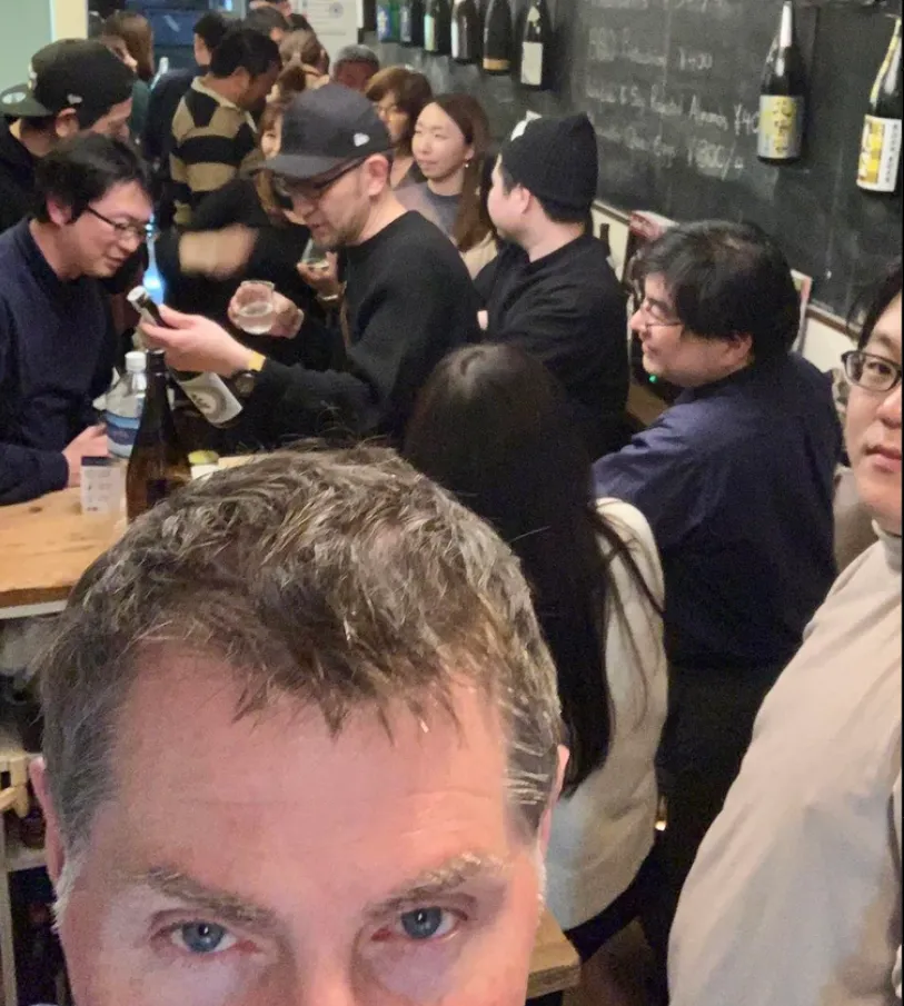 Guests sharing sake and conversation in the busy Yokohama bar