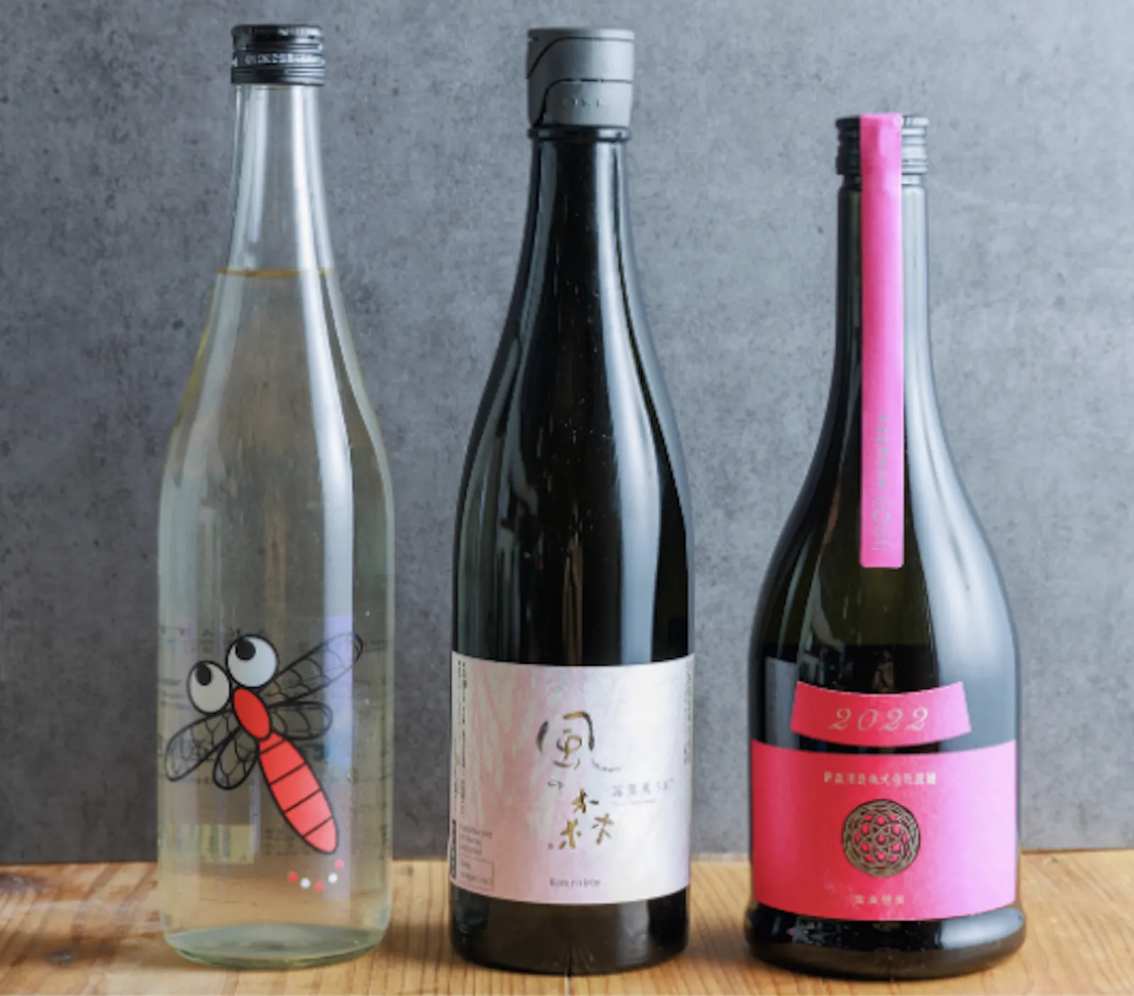 Three sake bottles with illustrated and pink labels