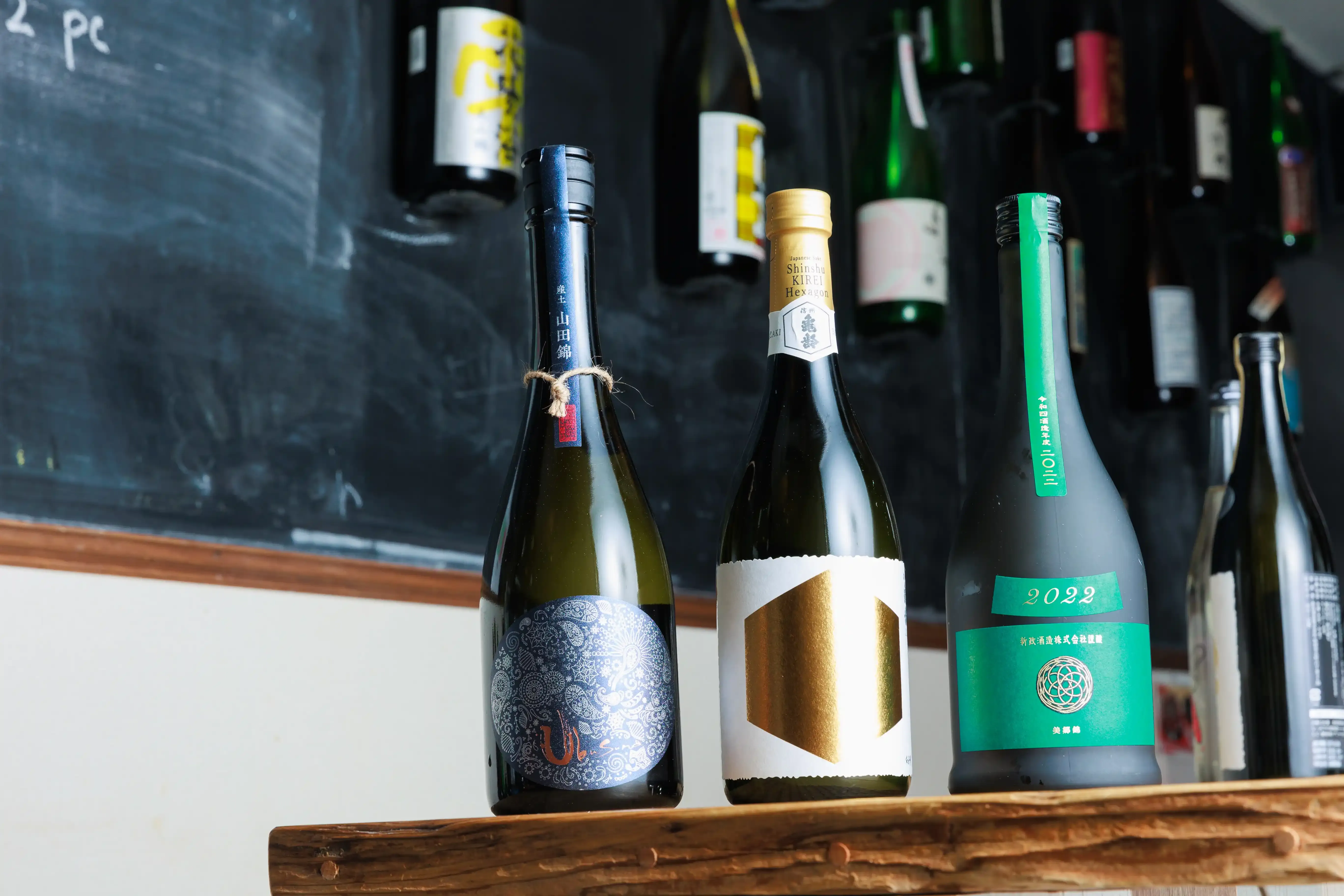 Sake bottles displayed on a wooden shelf at the Yokohama bar