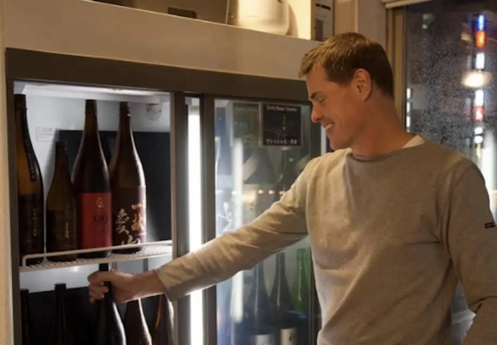 A person selecting a sake bottle from the Yokohama refrigerator